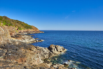 Image of the North Coast Cliffs, rocks and sea wtih clear blue sky, Jersey, Channel Islands, UK