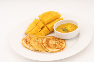 Breakfast pancakes on a plate with mango and sweet mango sauce.