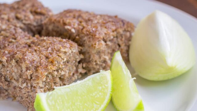 Kibe roast on white dish with lemmon and onion. Brazilian snack.