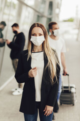 Fototapeta premium Portrait of young woman in protective masks near the airport. Safe travel during a coronavirus pandemic. Airplane travel, quarantine and pandemic concept