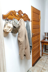 Fototapeta na wymiar Vintage wood wall coat rack/hanger with farmer's hats and coats