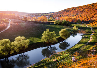 Beautiful landscape of summer hills with river in Moldova, Old Orhei. Zigzag river flows between valleys with willow trees and rocks at sunset. Travel background, Europe