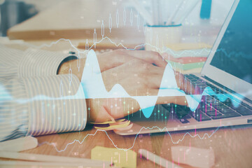 Multi exposure of stock market graph with man working on laptop on background. Concept of financial analysis.