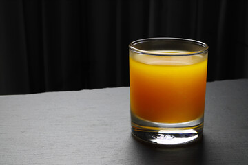 a glass of fresh and cool orange juice in the black background