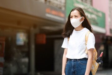 Asian girl in white t-shirt with yellow bag wear surgical mask to protect the Covid-19 virus in public areas, New normal lifestyle