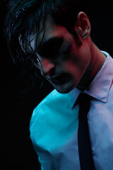 Portrait of a man in blue and red contrasting lighting in a white shirt and tie with a facial injury. Futuristic neon lighting.
