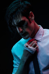 Futuristic neon lighting. Portrait of a man in blue and red contrasting lighting in a white shirt with a facial injury, bandaged hand