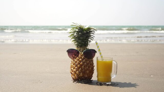 Tourist pineapple in sunglasses resting on the sea beach