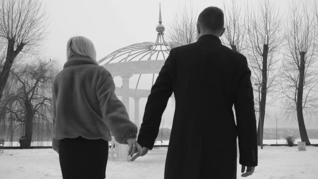 man and woman walking forward holding hands , blach and white. Slow motion