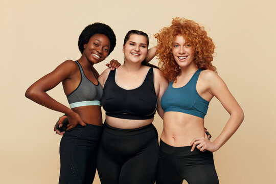 Diverse. Group Of Women With Different Figure Portrait. Smiling Multicultural Diversity Models In Fitness Clothes Posing On Beige Background. Body Positive As Lifestyle. 