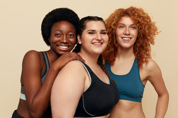 Diversity. Different Women Portrait. Smiling International Female In Fitness Clothes Posing Against Beige Background. Body Positive As Lifestyle.