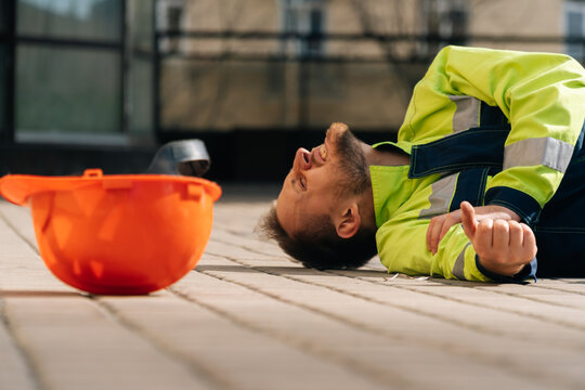 The builder fell after a hand injury at the elbow. Industrial accident concept. a young man has a broken arm