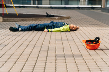 A young male builder died lies on the pavement in special construction clothing. Construction site accident