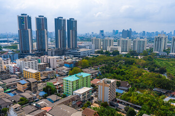 Fototapeta na wymiar View from the high floor of the streets of Bangkok. Tall buildings and roofs of small houses. City landscape