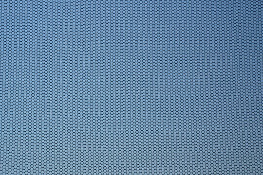 Close up of black fly screen with blue cloudless sky in background. Mosquito net fixed on a window. Insect screen. Contre-jour shot.