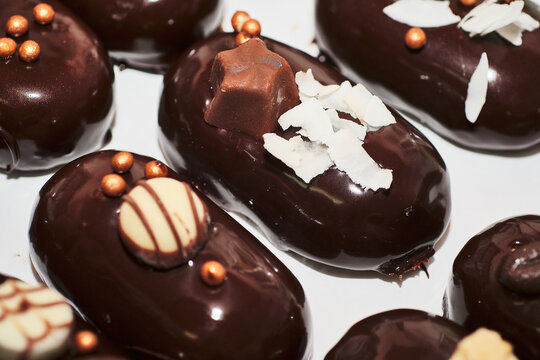 Luxurious event food. Fancy french dessert. Mini cakes glazed with shiny dark chocolate surface. Stuffed with delicious mousse and decorated with beautiful chocolate and sweet details.