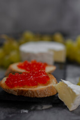 Camembert cheese with red caviar and white wine grapes