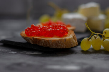 Camembert cheese with red caviar and white wine grapes