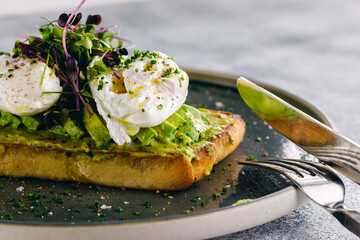 Guacamole and poached egg bruschetta served with greens and sliced avocado