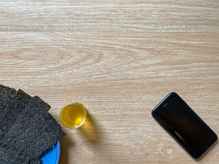 Crispy seaweed with hot green tea, morning snack  And have a smartphone on the right background is a brown wood pattern with copy space. Concept for relaxing. Home holiday Simple morning. top view.