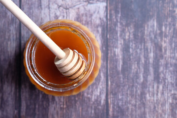 Top view of fresh honey in a jar on wooden table.