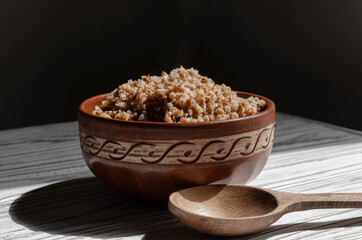 buckwheat porridge in a clay plate with butter and a wooden spoon