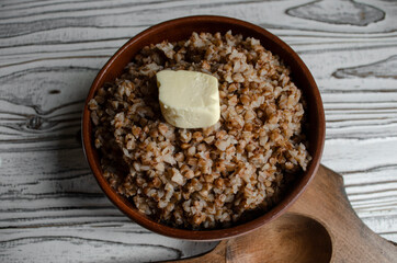 buckwheat porridge in a clay plate with butter and a wooden spoon