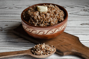 buckwheat porridge in a clay plate with butter and a wooden spoon