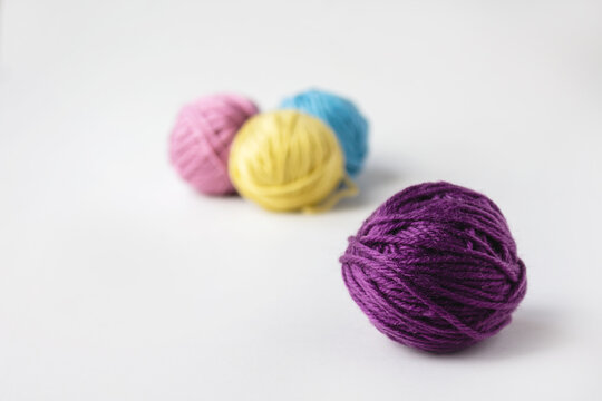 Close up of violet woolen ball. Three other woolen balls in background on light backdrop.