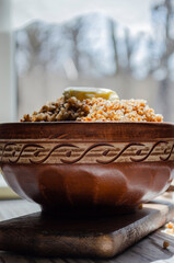 buckwheat porridge in a clay plate with butter and a wooden spoon