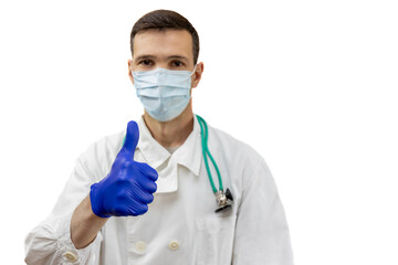 Young doctor with stethoscope in  protective mask and gloves showing thumbs up sign isolated on white background. Focus on hand.