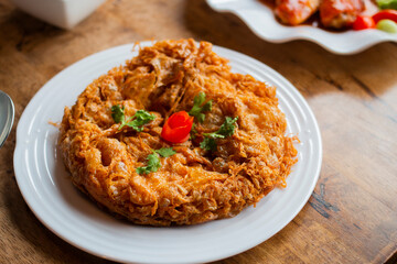 Top view of delicious Thai style omelet serves on white plate on wooden table.