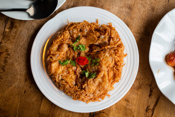 Top view of delicious Thai style omelet serves on white plate on wooden table.
