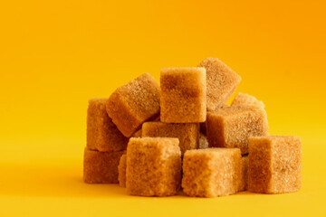 brown sugar cubes on a yellow background, selective focus, free copy space 