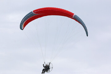 Paramotor pilot flying in a blue sky