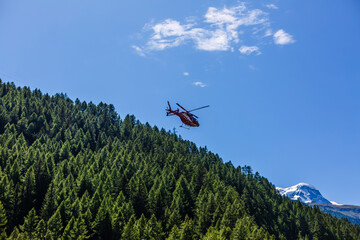 Fototapeta na wymiar red helicopter flying over the alps