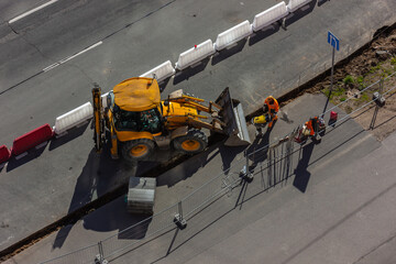 Repair work on the city streets using a heavy loader with a bucket for the construction of the...