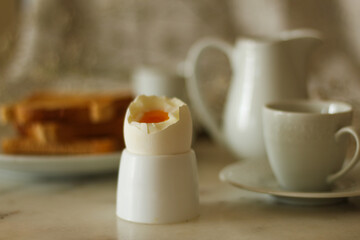 Simple breakfast concept: boiled egg in focus and rest like toast, coffee cup in selective focus