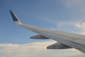 view from plane window looking out over the wing towards the blue sky beyond.