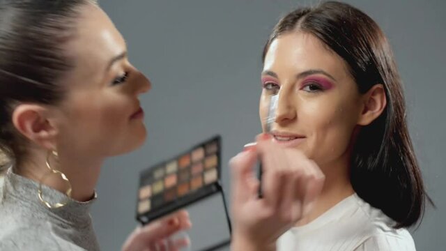Make up artist working and making a vlog while putting make up to a girl. Creating videoblog content for podcast or streaming live youtuber