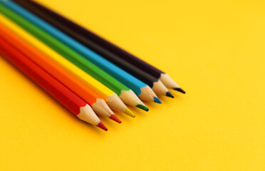 pencils placed in order of rainbow colors on yellow background, selective focus, free copy space