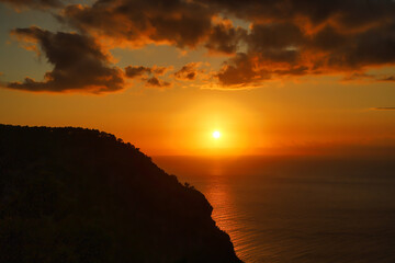 Naklejka premium Sunset over sea with clouds and mountain rock in dusk – Mallorca coast, Spain