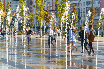 Photography of teenagers running through the fountains set. Concepts of walking, happiness,...