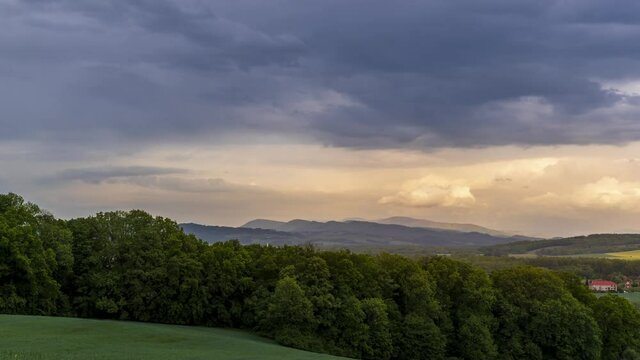 Timelapse of sunset over a mountainous landscape full of orange hills changing the landscape around lying towns and houses during a rainy morning Hranice na Morave Czech Republic