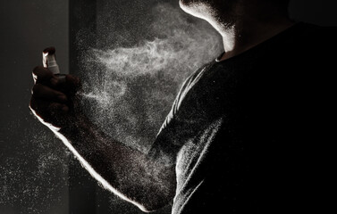 man push on parfume. Spray can with fume coming out on black background