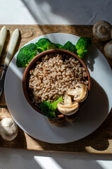 buckwheat porridge in a clay plate with butter and broccoli