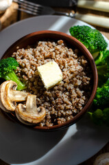 buckwheat porridge in a clay plate with butter and broccoli