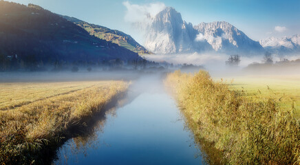Obraz premium Wonderful picturesque Scene. Amazing Misty Morning. Beautiful nature Scenery. scenic view of Majestic Mountain Peak with river foreground, shoot in morning in Autumn season, Fantastic Alpine Landscape