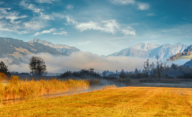 Wonderful panorama in foggy morning with glaciers mountain and River in the valley on foreground. Fantastic sunny morning in alpine valley during sunrise. Amazing Natural Background. Autumn landscape