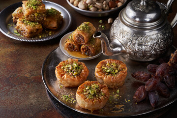 Middle eastern arab sweet pastry baklava, different delights, dried dates, pistachios, honey on a dark rusty background. Selective focus. Ramadan, Eid concept.